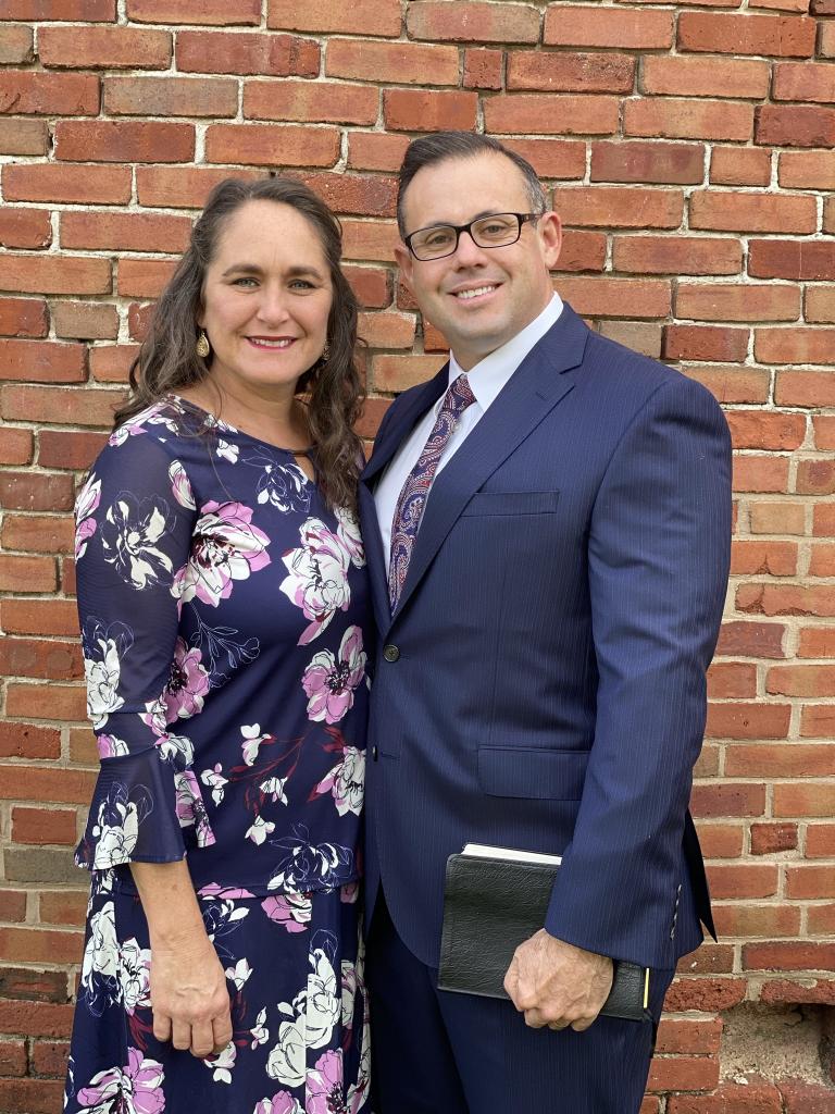 Pastor and his wife standing in front of red brick building